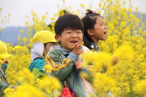 本当の笑顔は自然とこぼれる。一面の菜の花畑に思わず微笑む園児