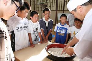 高椋小学校の校長の永谷彰啓さんがそば打ちを指導