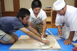 きれいに伸ばした生地を破れないように慎重に折りたたみながら、切る作業に入る子どもたち