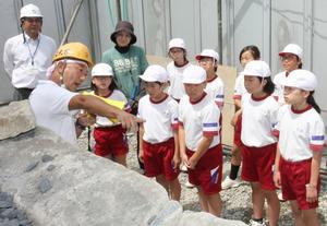 実施に使われている石を見ながら説明を受ける児童たち