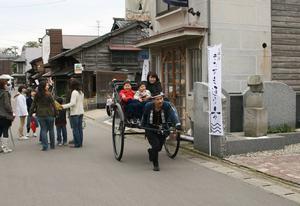 人力車に乗って、湊町の風情を感じる観光客