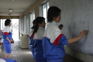 水をつけたたわしで待合室の壁の汚れを落とす女子生徒