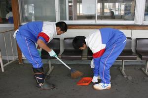 ベンチの下のごみも丁寧に掃きとる男子生徒