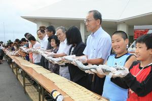 完成した寿司を持ち上げ、笑顔を見せる参加者