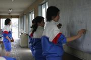 水をつけたたわしで待合室の壁の汚れを落とす女子生徒