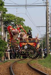 武者人形を後ろに倒し、バランスをとりながら慎重に線路を渡る下錦区の人形山車