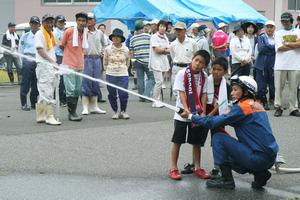 消防士が補助をして放水体験をする子どもたち