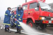 仲間と協力してポンプ車による放水を行う団員ら