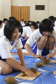 細長く伸ばし、輪状にした粘土を重ねて埴輪を作っていく児童たち