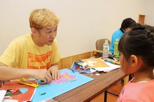 目や口の大きさなどを子どもたちに聞いて切り抜く木村さん