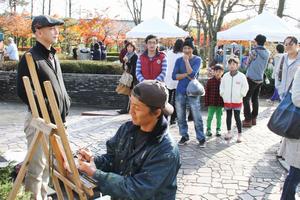 会場で地元アーティストのDAISUKE(だいすけ)氏がエアーブラシを使って似顔絵を作成