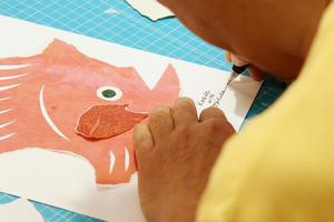 木村さんがカッターで切れ込みを入れて完成した作品には、子どもたちと木村さんのサインを記名