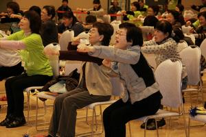 運動機能の低下による寝たきりなどを予防する体操。楽しみながら体を動かす来場者