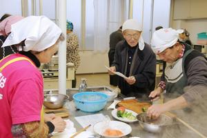 「ミートローフ」「鮭と大根の和風スープ」など4品を手分けしながら調理する参加者たち