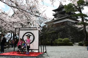 丸岡城と桜をバックに記念撮影をする親子ら