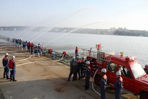 防災道路から川に向かって一斉放水を行う団員ら