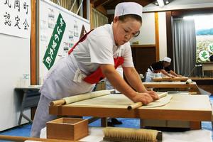 集中力を欠かさずに、こねたそば粉を延ばしていく出場者たち