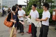 早朝の駅で通勤する人にチラシとうちわを配る春工の生徒会役員ら