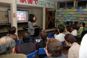 読み聞かせボランティアの西山式子氏が長屋に伝わる「まつやのびんづけ」について、画像を交えて話す