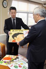 教育長に寄贈する大型絵本の目録を贈呈する寺井支部長