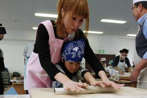 ラップの芯でそば粉を延ばす親子。ラップの芯は十分硬く、潰れることなく使用できた