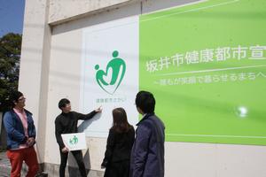 本庁舎別館1階外壁に設置された看板。「坂井市健康都市宣言」などの白い文字は車のライトを反射し光る