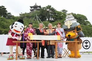発起市の青森県弘前市・葛西憲之市長(中央右)が持参した同盟の巻物に署名し、固く握手を交わす市長ら
