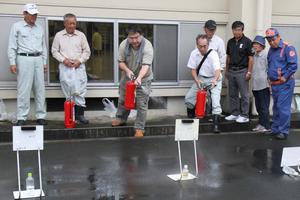 初期消火訓練をする参加者。ほうきで掃くイメージで、根元から消すようにアドバイスを受ける