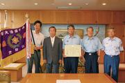 ポンプ車操法の部での優勝を賞状と旗で報告する分団長の上田幸生さん(中央)ら