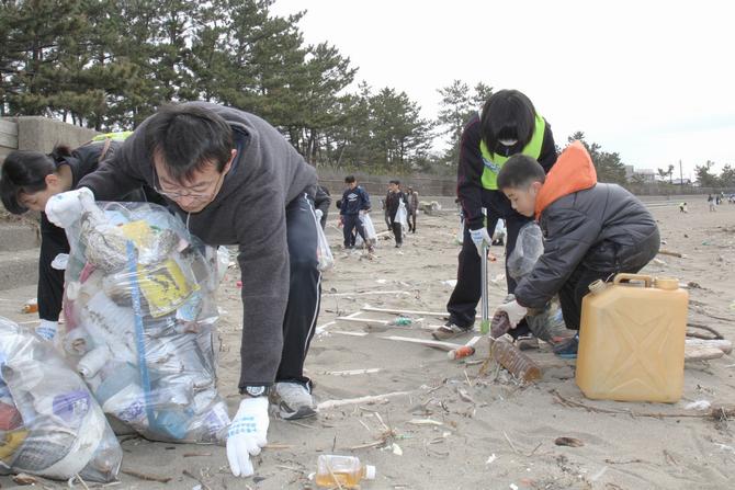 コツコツとごみを拾い、砂浜を奇麗にしていく家族。